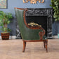 Vintage green leather armchair with wooden frame in a room with marble fireplace and plants.