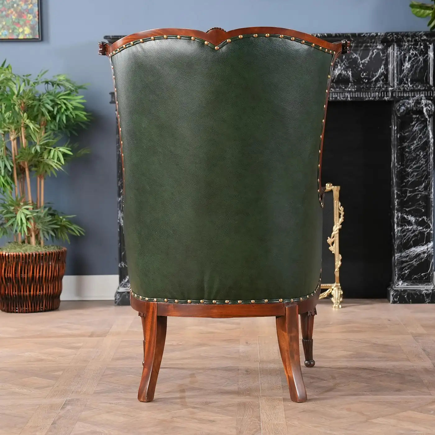 Green upholstered chair with wooden frame in a room with a fireplace and plants.