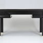 Black console table with gold accents on a gray background