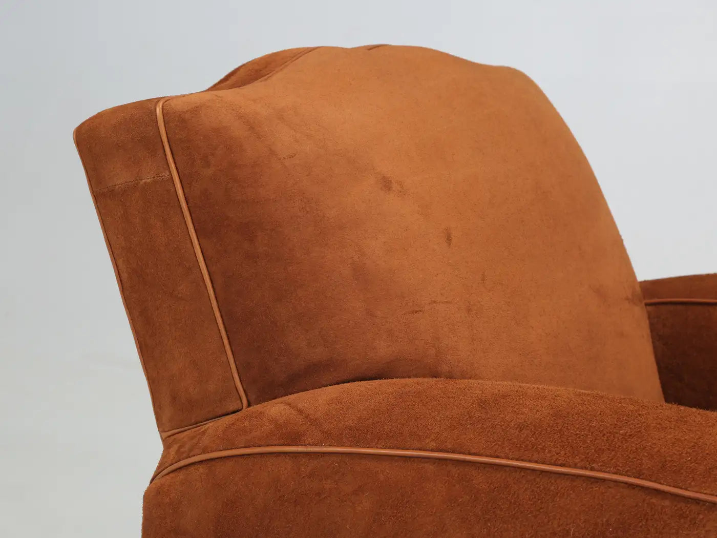 Close-up of a brown suede armchair on a light gray background