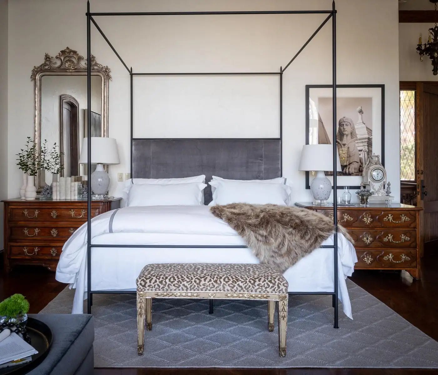 Neatly made bed with a canopy in a bedroom setting.
