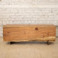 Wooden bench with a rustic design against a white brick wall.