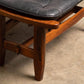 Wooden stool with a black leather seat on a beige carpet