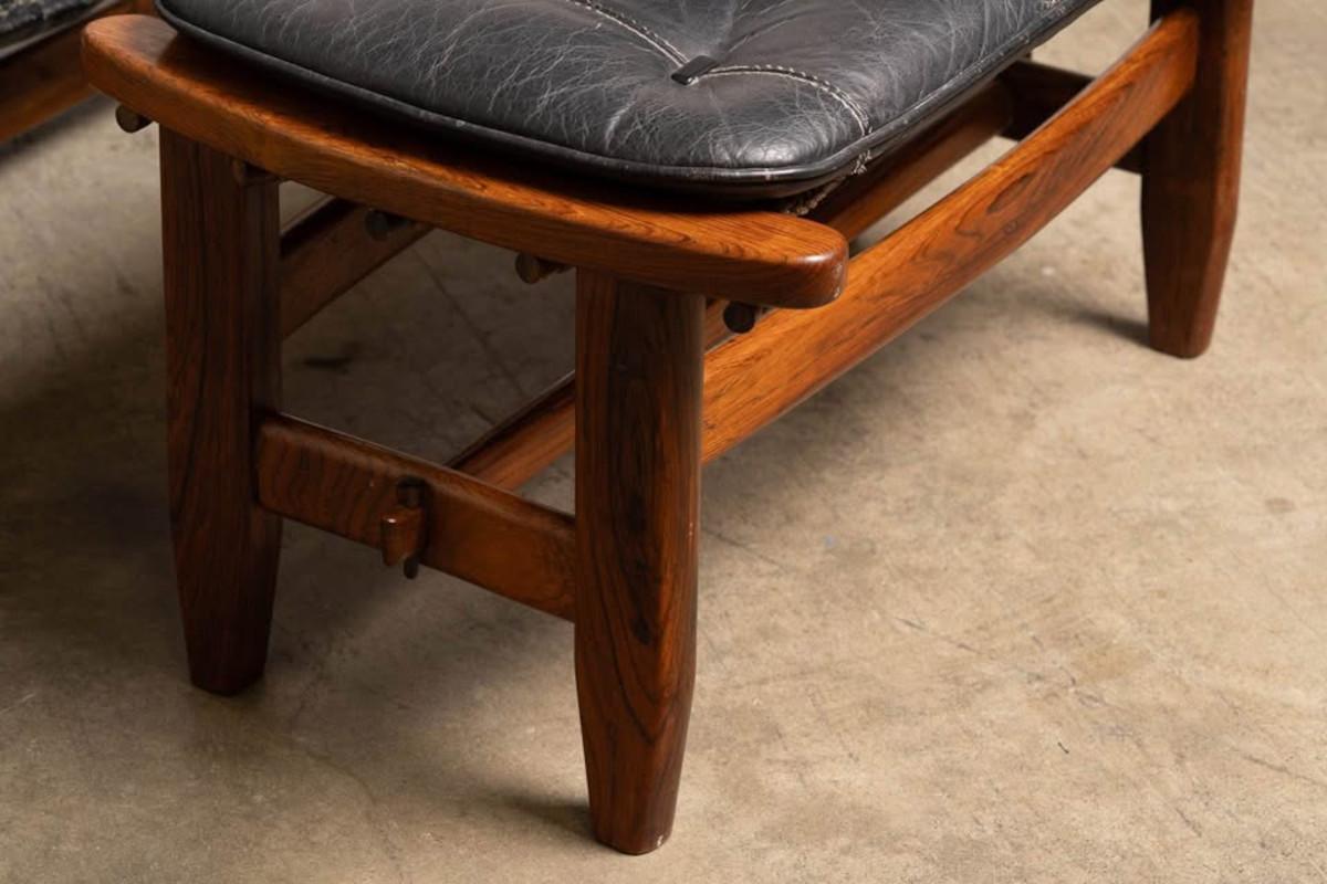 Wooden stool with a black leather seat on a beige carpet