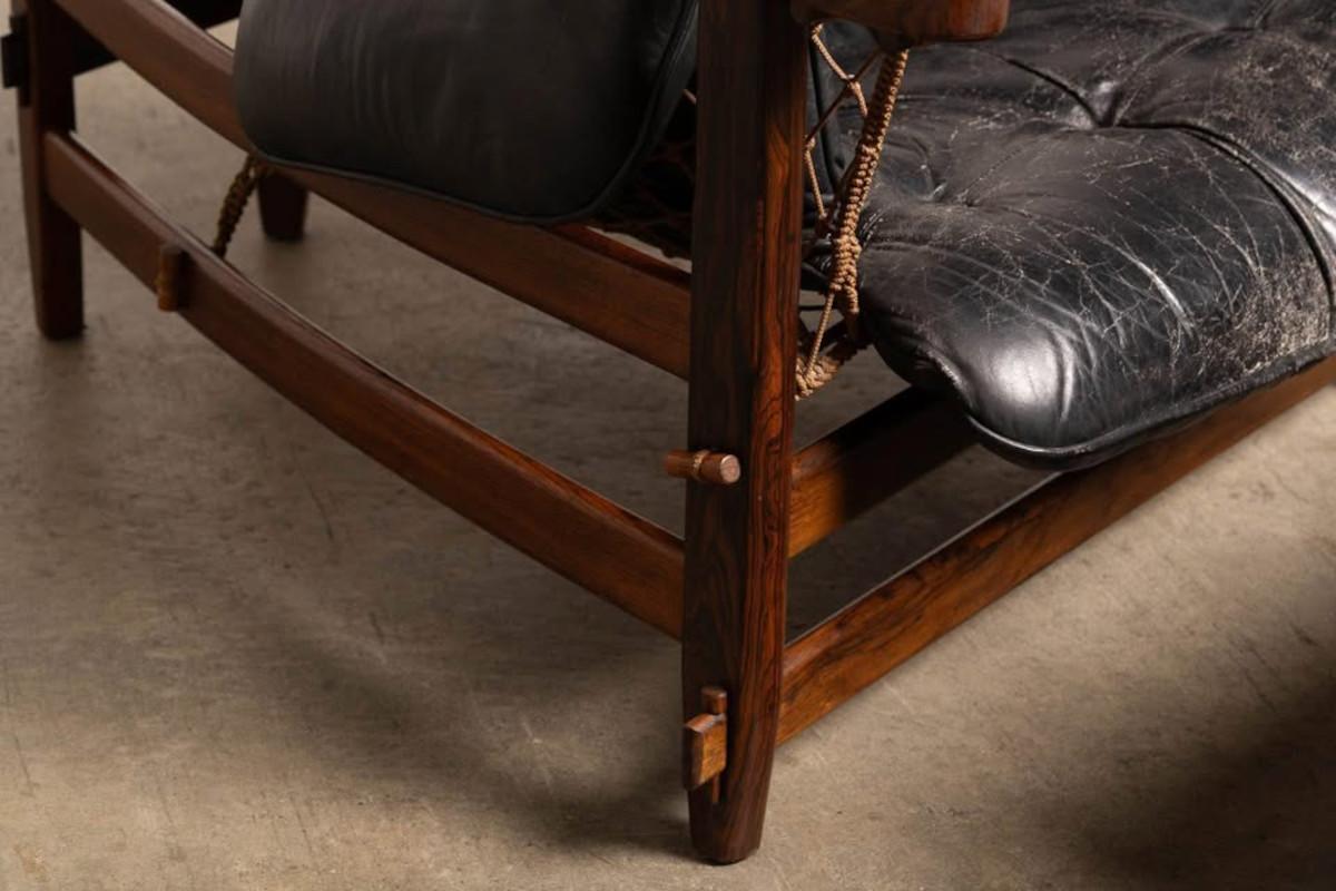 Close-up of a wooden chair with black leather cushion on a concrete floor