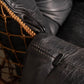 Close-up of a black leather chair with brown woven backrest