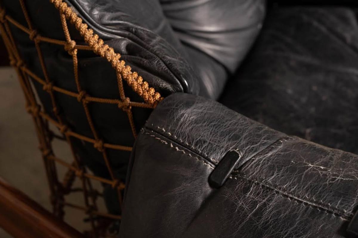 Close-up of a black leather chair with brown woven backrest