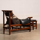 Wooden lounge chair with black cushion on a plain floor and wall background