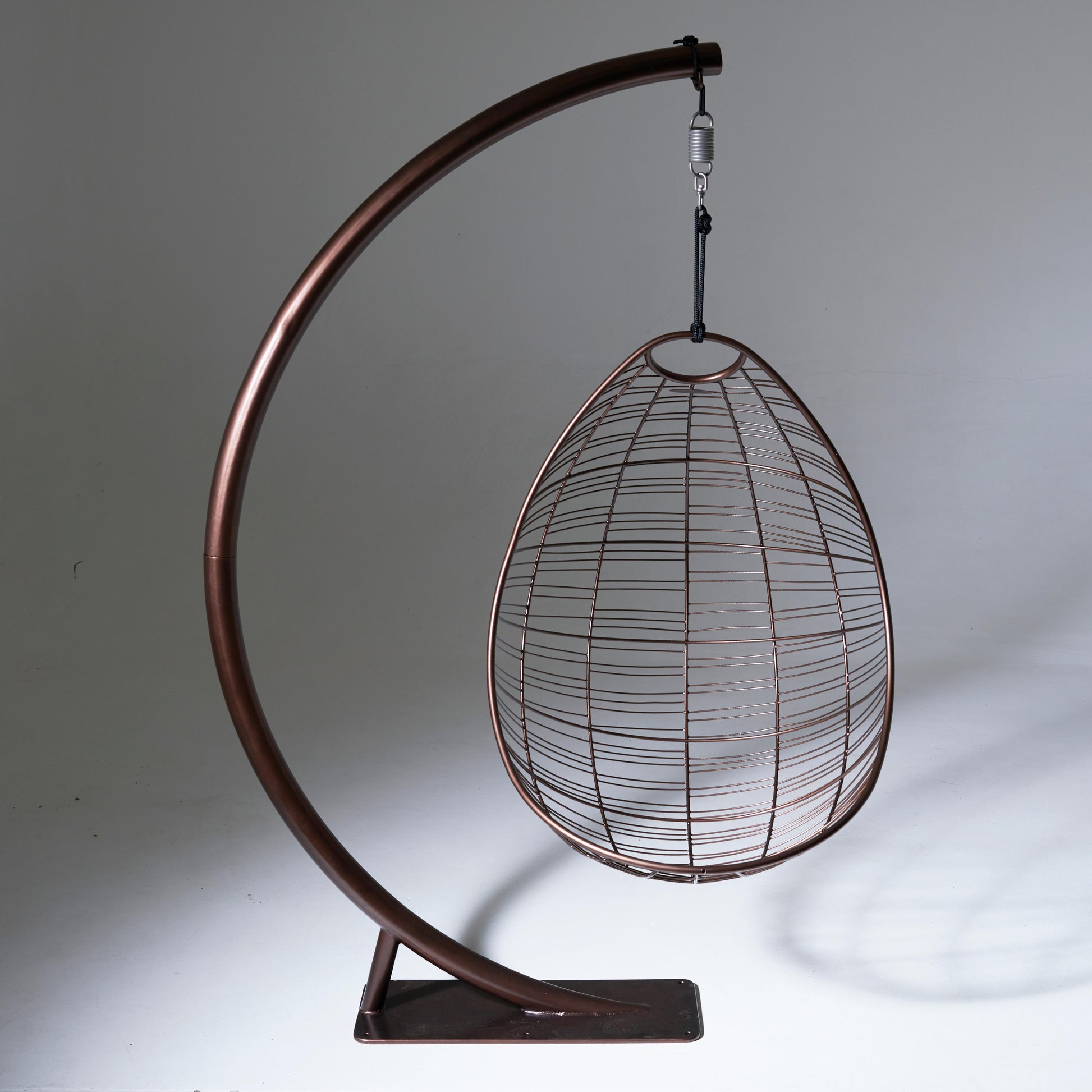 Wire egg-shaped chair hanging from a curved metal stand on a gray background
