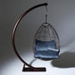 Hanging chair with blue cushions on a dark metal stand against a gray background