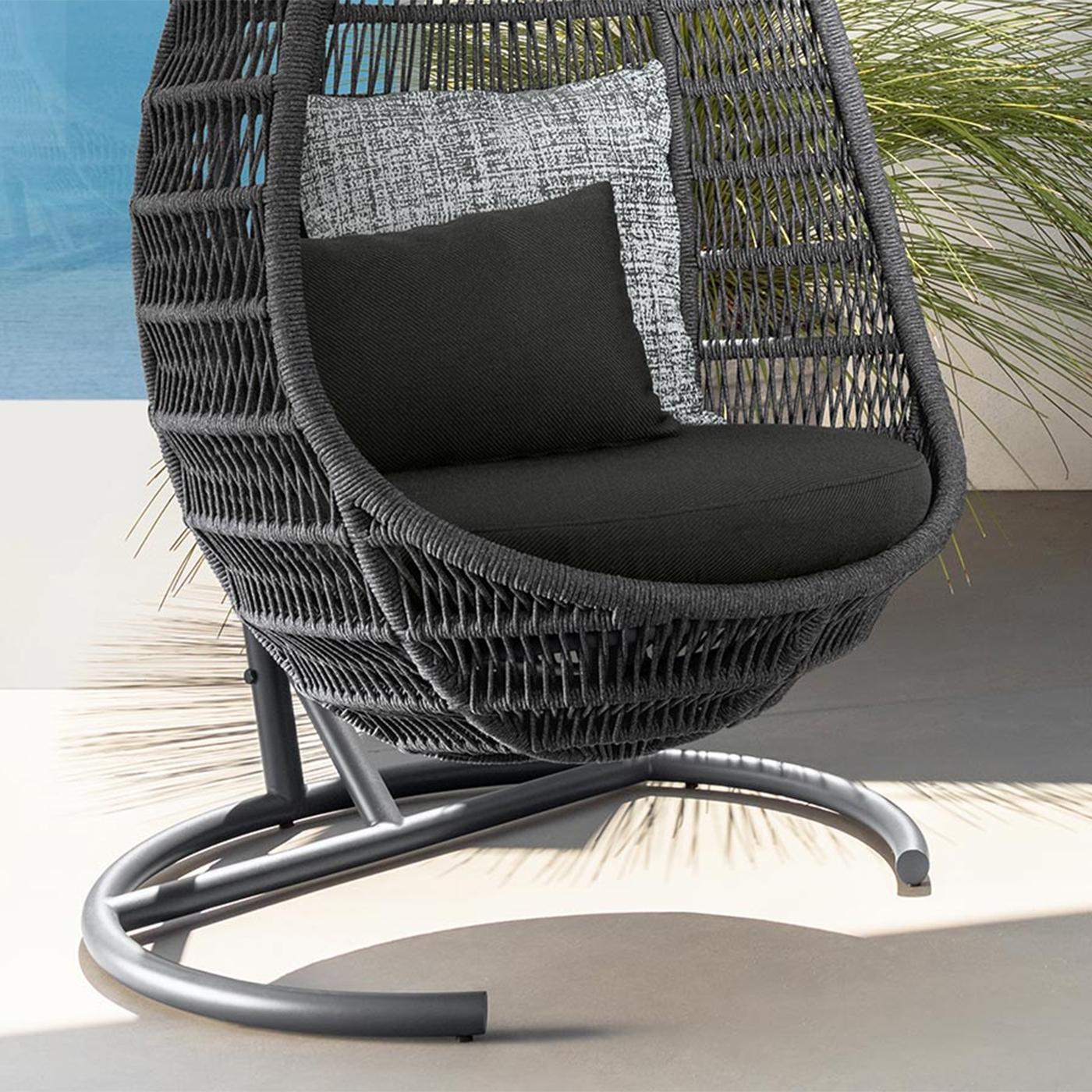 Gray wicker egg chair with black cushions on a light surface.