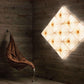 Wall-mounted light fixture casting a warm glow on a wooden wall with a hanging chair.