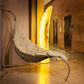 Hanging chair in a modern indoor setting with a large decorative light in the background.