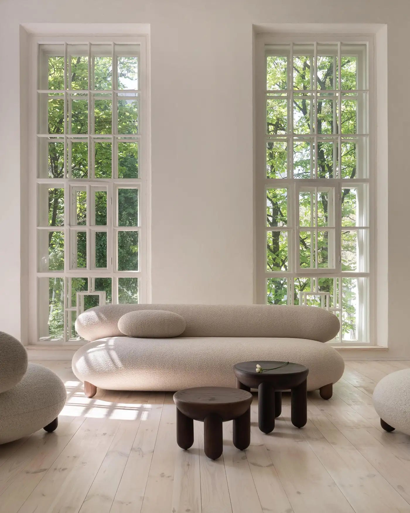Modern beige sofa in a room with large windows and wooden flooring