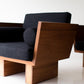 Modern chair with wooden frame and dark cushions on a white background