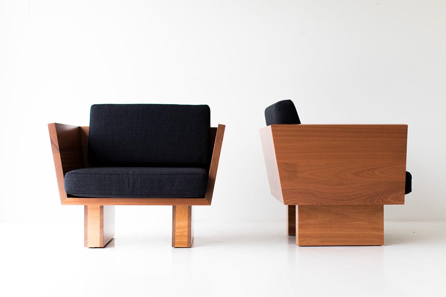 Two modern chairs with wooden frames and black cushions on a white background