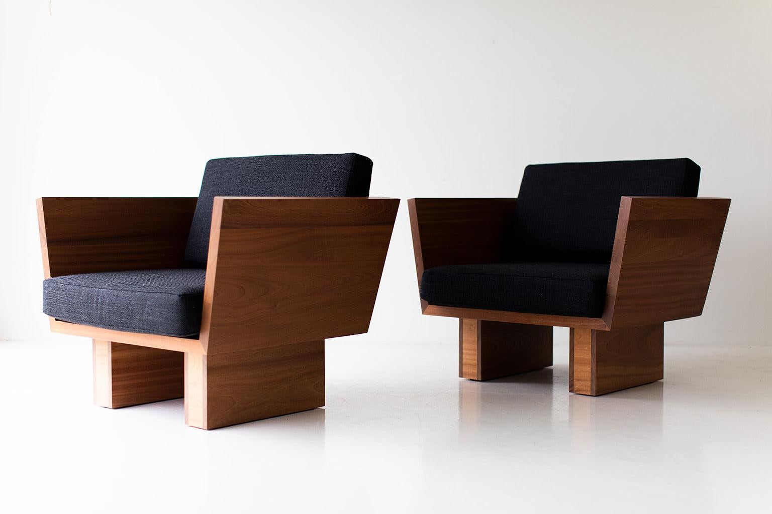 Two modern chairs with wooden frames and black cushions on a white background