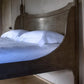 Wooden bed with white bedding in a softly lit room