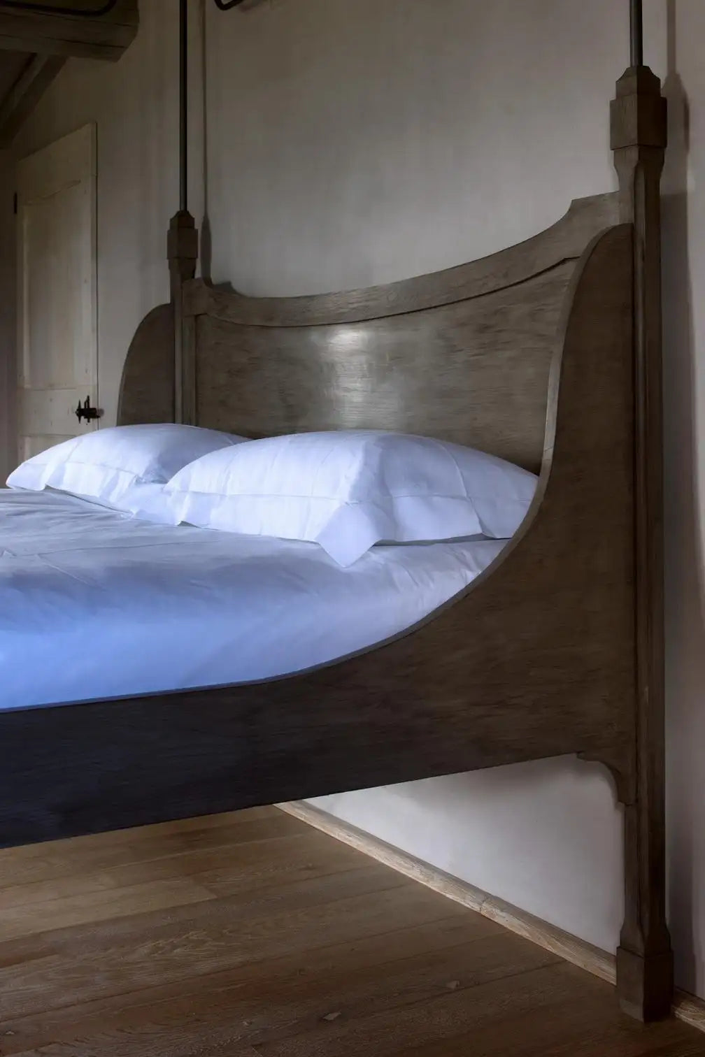 Wooden bed with white bedding in a softly lit room