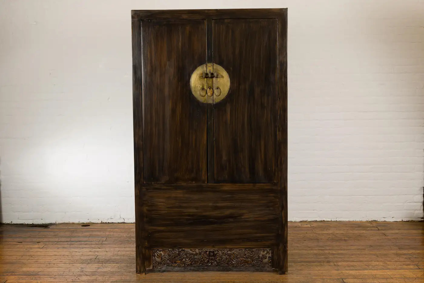 Wooden wardrobe with circular emblem on a white brick wall background