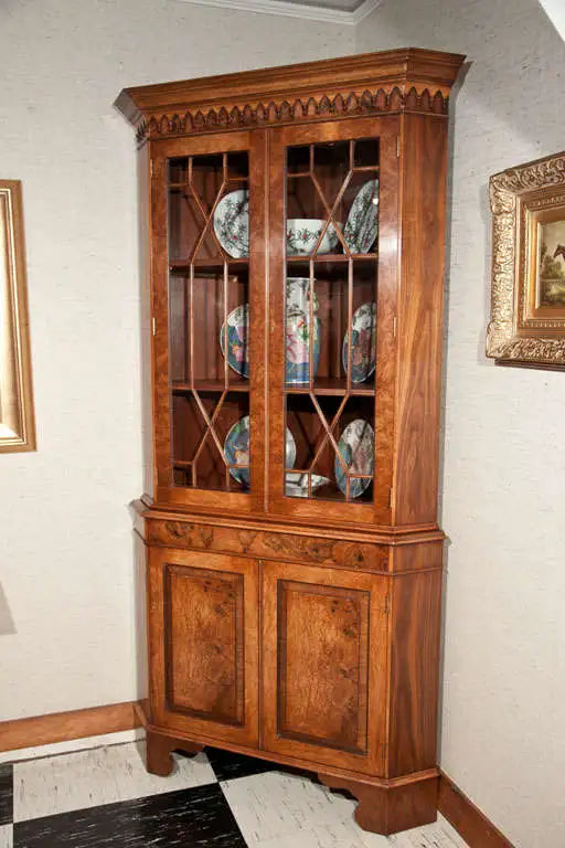 Wooden corner cabinet with decorative plates inside, against a light-colored wall.