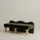 Green velvet bench with wooden legs on a beige background