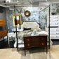 Bedroom setting with a canopy bed, dresser, and floral wallpaper.