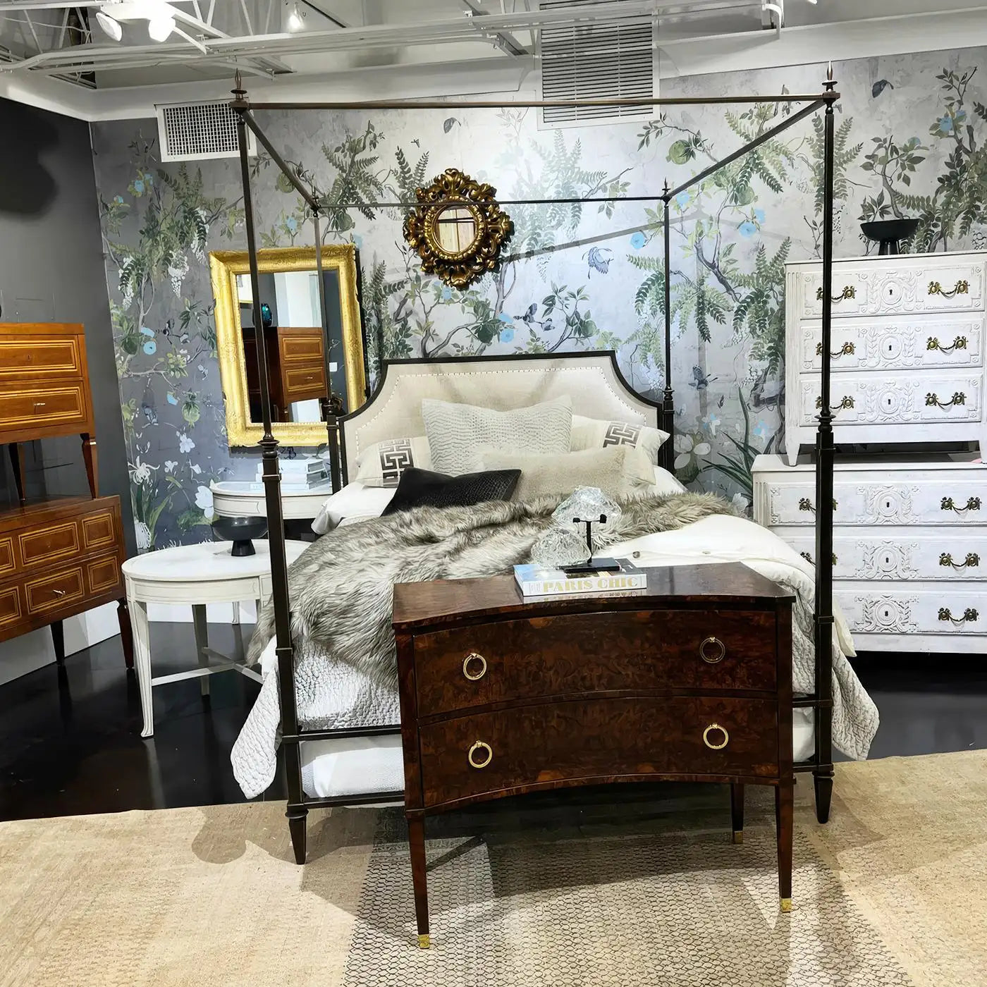 Bedroom setting with a canopy bed, dresser, and floral wallpaper.