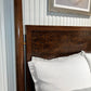 Wooden headboard with white pillows against a neutral wall.