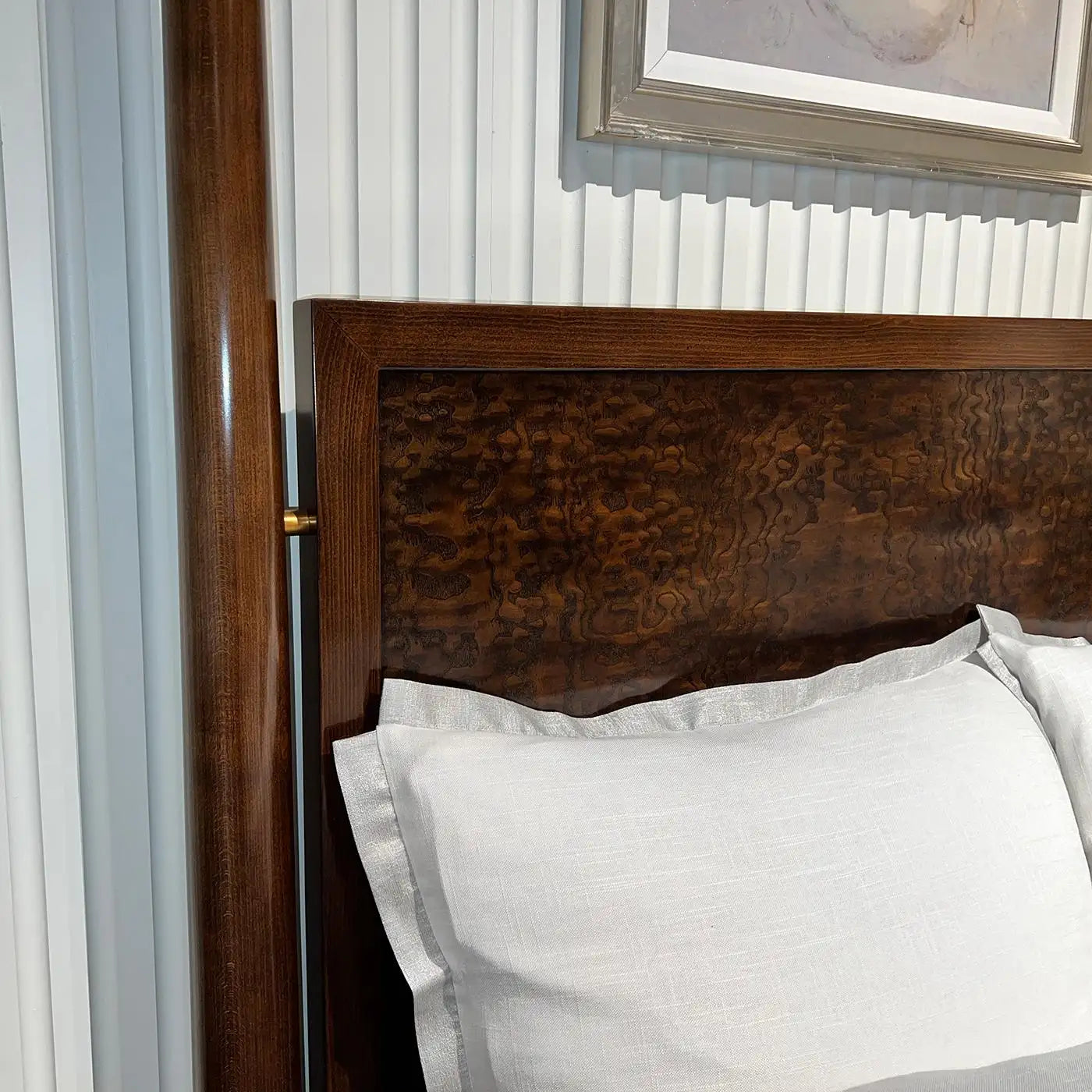 Wooden headboard with white pillows against a neutral wall.