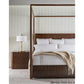 Bedroom with a four-poster bed, nightstand, and lamp against a striped wall.