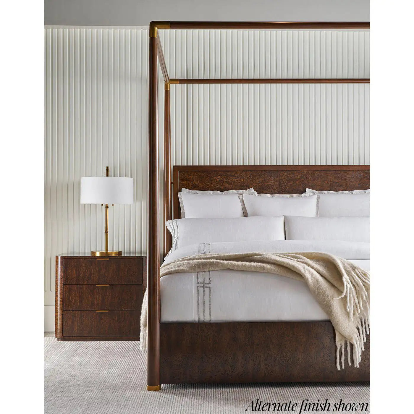 Bedroom with a four-poster bed, nightstand, and lamp against a striped wall.