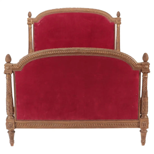 Decorative bed with red velvet upholstery and gold frame on a white background