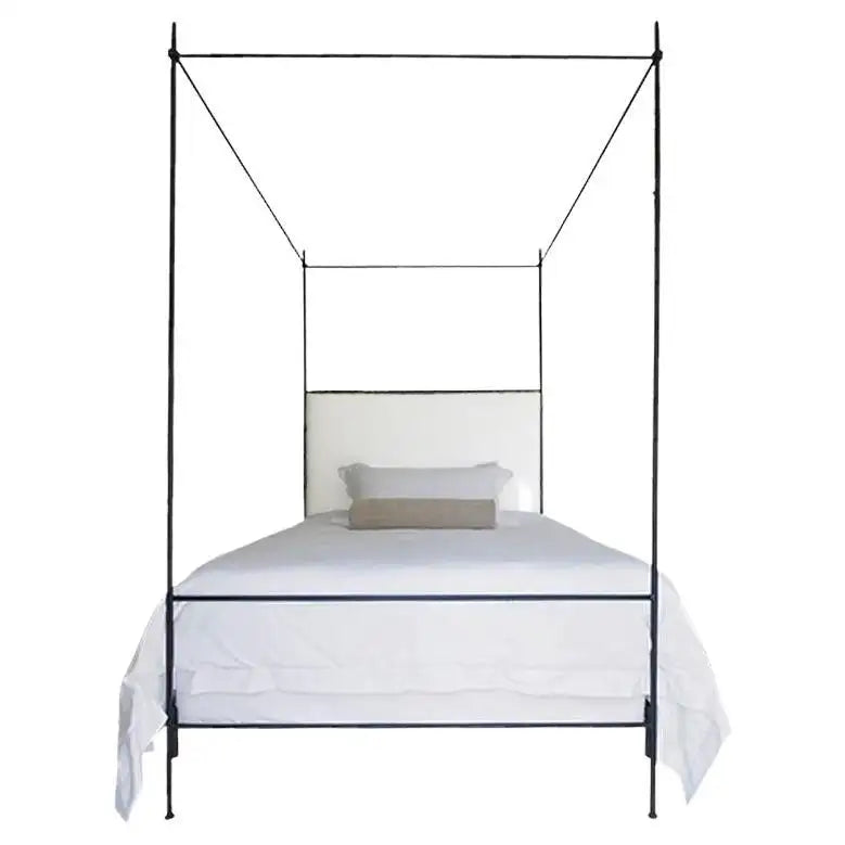 Black metal canopy bed with white bedding on a white background