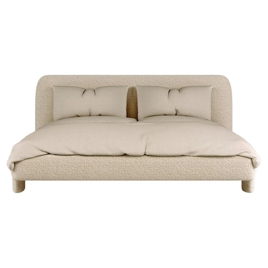 Beige upholstered bed with pillows on a white background