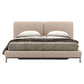 Beige upholstered bed with bedding on a white background