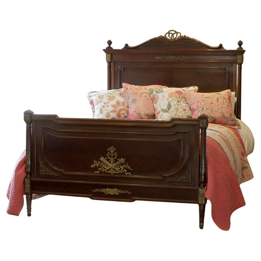 Vintage-style wooden bed with floral bedding on a white background