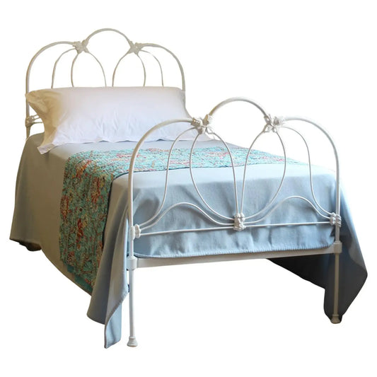 White metal bed with decorative headboard and bedding on a white background