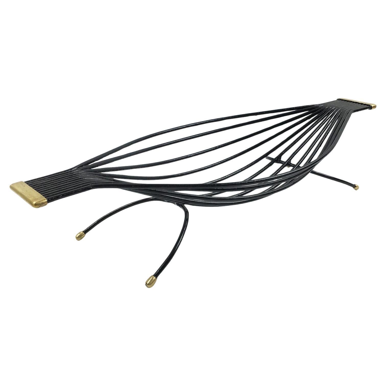 Black metal leaf-shaped object with gold accents on a white background
