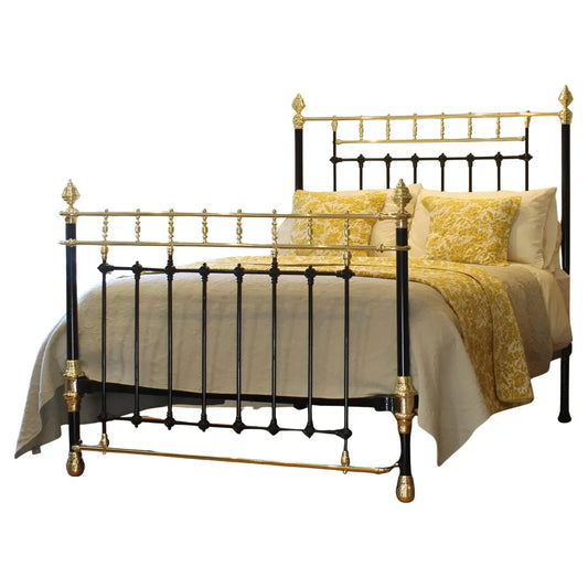 Decorative bed with gold and black metal frame and yellow bedding on a white background