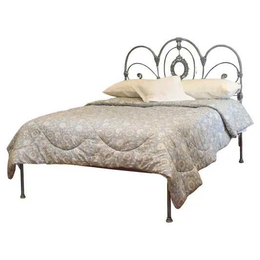 Decorative bed with intricate metal headboard and patterned bedding on a white background