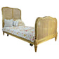 Wicker bed with floral bedding and pillows on a white background