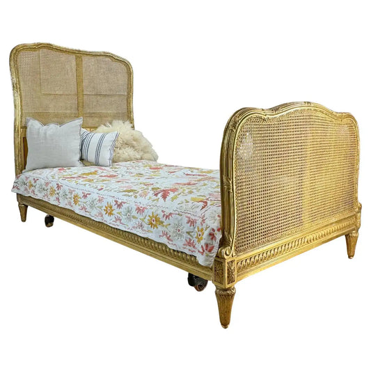 Wicker bed with floral bedding and pillows on a white background