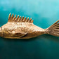 Bronze fish sculpture on a teal background
