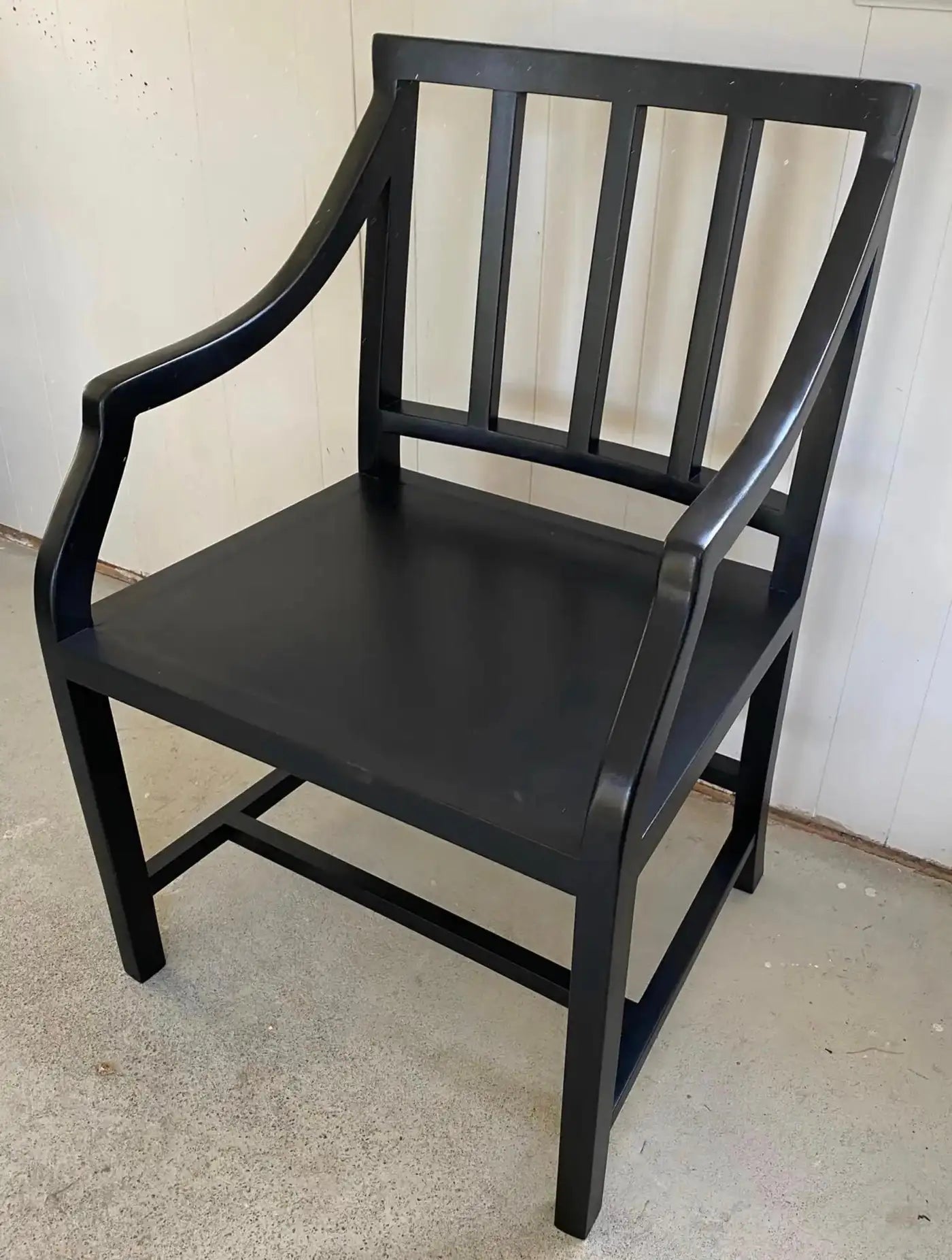 Black wooden chair against a white wall