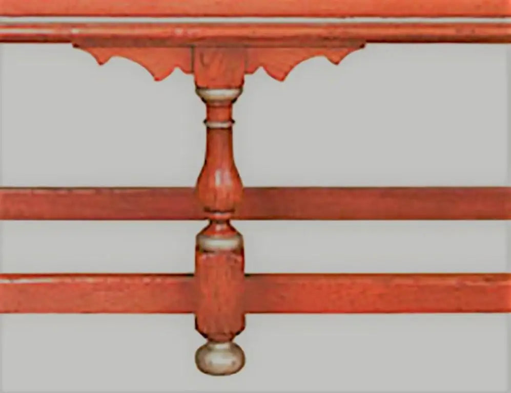 Close-up of a red wooden bed frame with decorative carvings on a light gray background