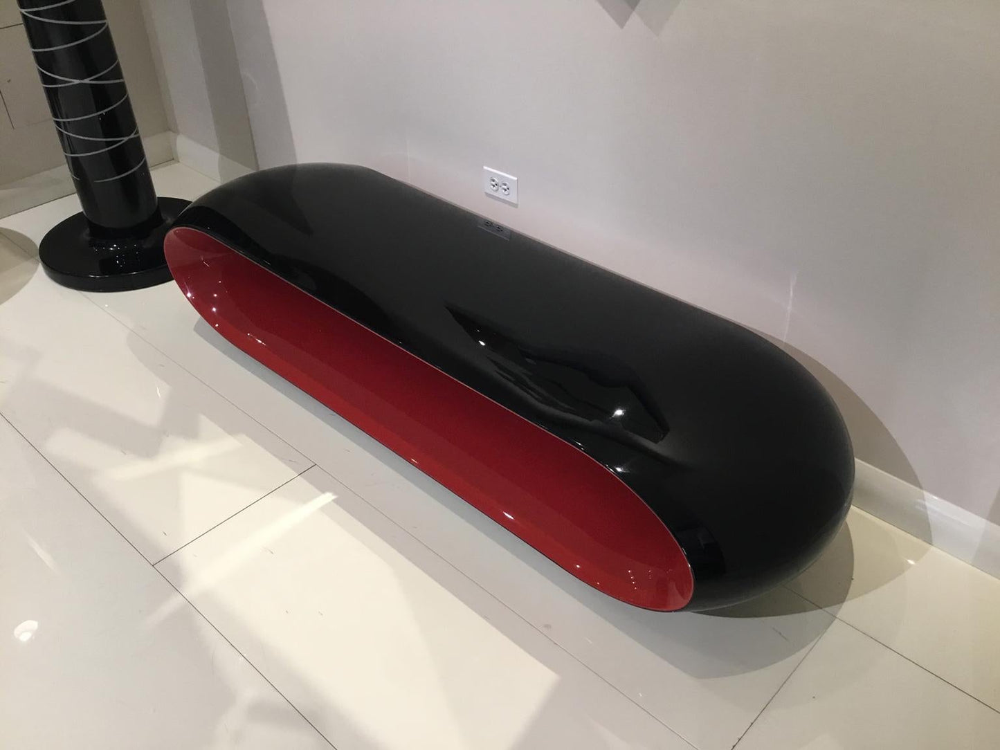 Black and red oval-shaped object on a white floor