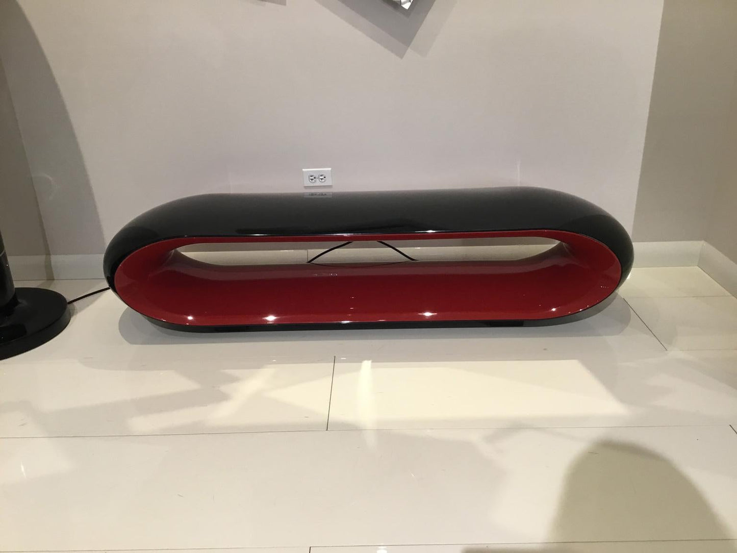 Modern black and red oval object on a white surface