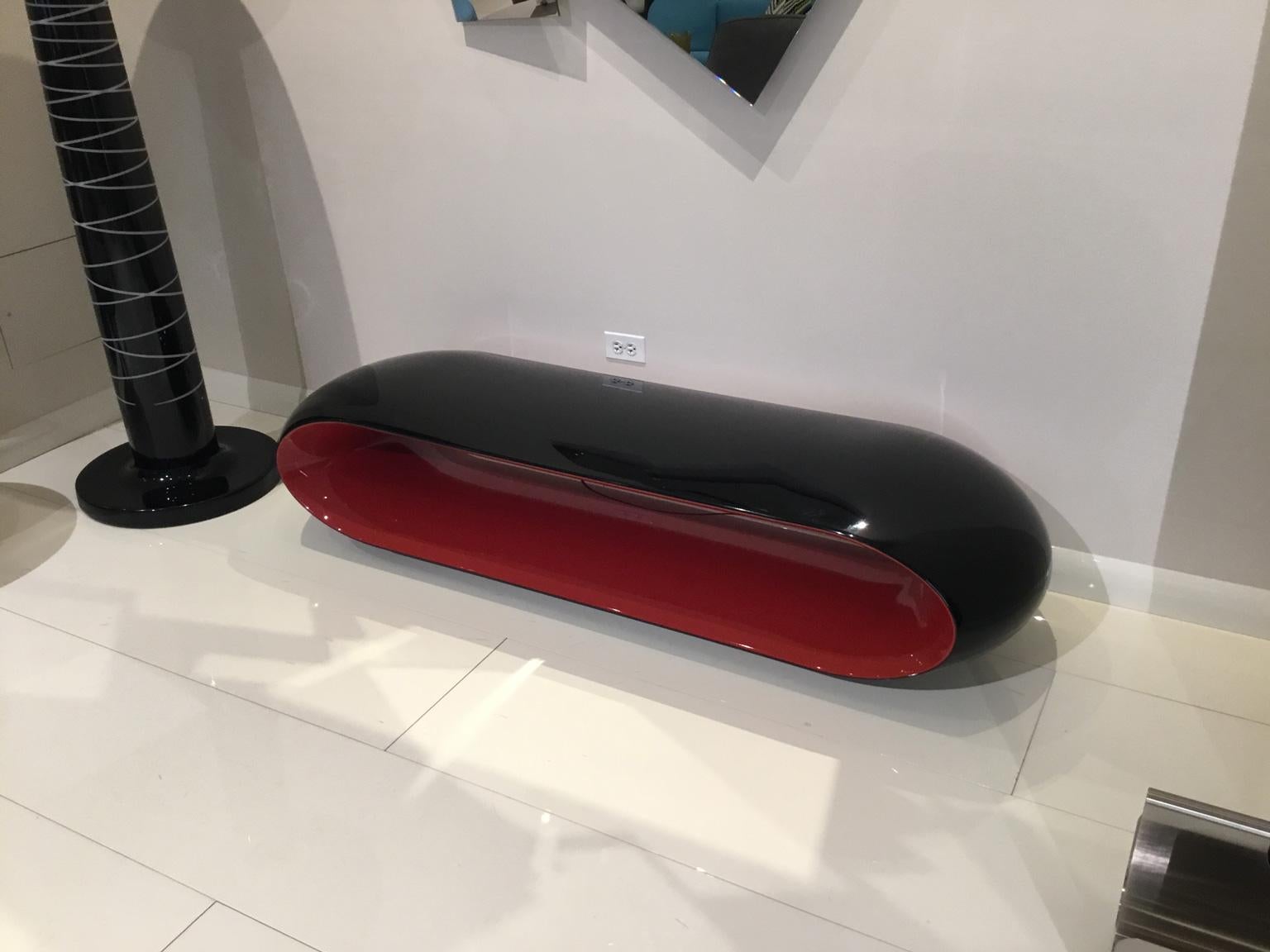 Modern black and red oval bench on a white tiled floor