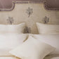 Beige headboard with leaf patterns and matching pillows on a bed.